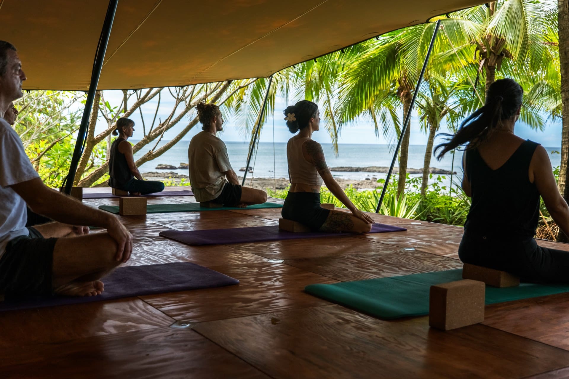 Clase de yoga grupal en el deck con vista al océano